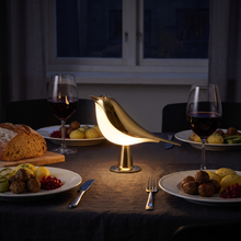 Cora i guld som enda ljus på ett dukat middagsbord för två